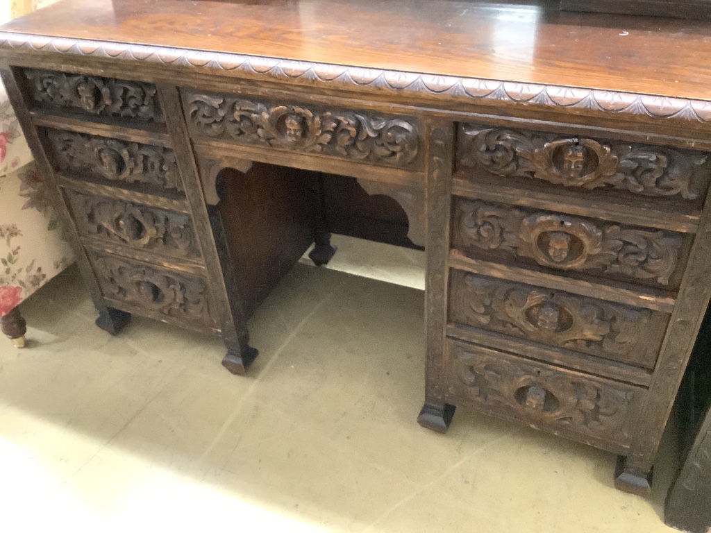 A late 19th century Flemish carveed oak kneehole dressing table, width 136cm depth 56cm height 183cm